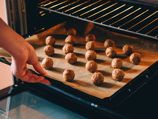 Raw frozen meat balls on baking sheet with paper