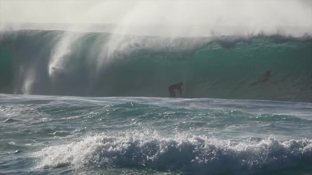 Surfers surfing massive waves. Big swell with huge waves hitting the shoreline