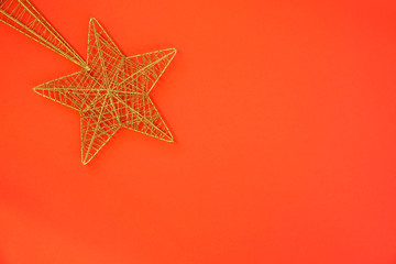 Close up of gold glitter christmas decoration star on red background. Empty blank copy space for text.