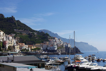 Fototapeta na wymiar View of Amalfi across boats in harbour to mountains, Italy