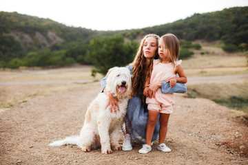 A family with a large dog and a small child in the mountains. View from the back. Space for text.