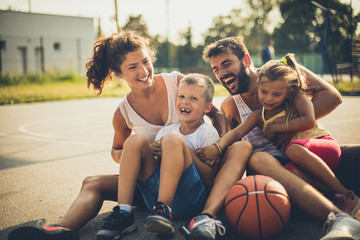Fototapeta na wymiar Portrait of family with two children at basketball playground.