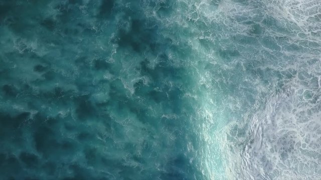 Big Waves rolling from above. Top down on blue ocean, breaking waves whitewash