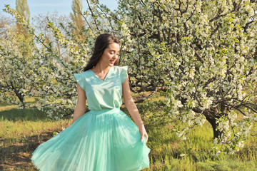 Fototapeta premium Beautiful young woman near blossoming tree on sunny spring day