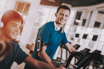 Young Father and Son Training on Treadmills in Gym