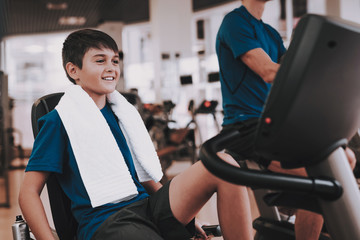 Young Father and Son Training on Treadmills in Gym