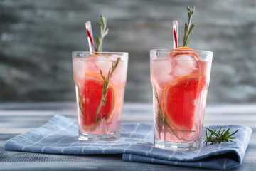 Fresh grapefruit cocktail with rosemary in glasses on wooden table