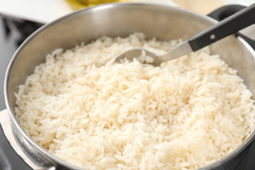 Saucepan with boiled rice on stove, closeup