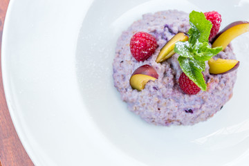 Oatmeal porridge with blueberries, raspberries and peach.