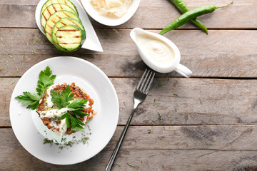 Plate with tasty zucchini pancakes on wooden table