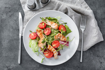 Plate with tasty chicken salad on grey table