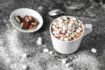 Cup of delicious cocoa with marshmallows and chocolate on grunge table