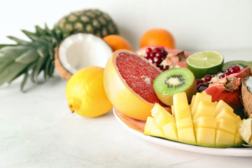 Fototapeta na wymiar Plate with various delicious exotic fruits on light table