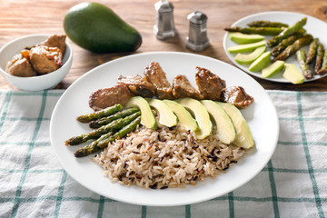 Plate with boiled rice, vegetables and meat on table
