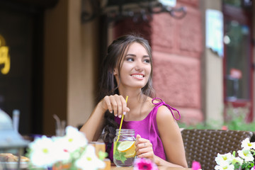 Young woman drinking fresh lemonade in cafe