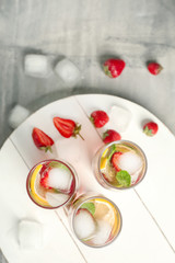 Obraz na płótnie Canvas Glasses of fresh strawberry lemonade on wooden board