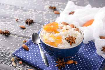 Bowl with delicious rice pudding and dry apricots on table