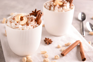 Cups with delicious rice pudding and nuts on napkin