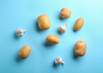 Obraz premium Potatoes and garlic on color background, flat lay