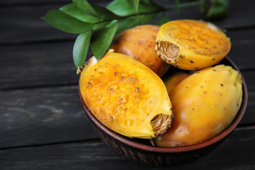 Bowl with ripe cactus pears on wooden table