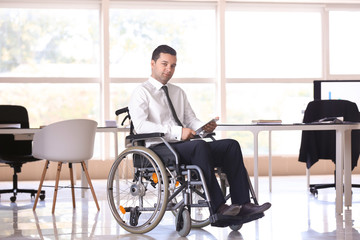 Businessman in wheelchair working with tablet PC indoors