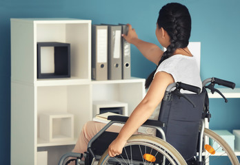 Asian woman in wheelchair looking for documents in office