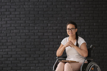 Fototapeta na wymiar Female teacher in wheelchair near brick wall