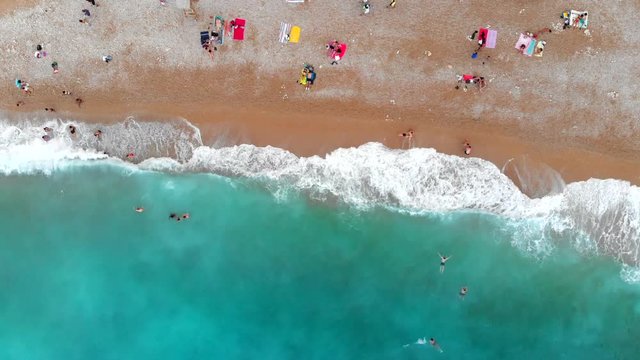 People relax sunbathing and bathe on the sandy beach on the Mediterranean coast azure color. Spain, Valencian Country,  Province of Alicante,  Costa Blanca,  Benitachell, Cala del Moraig, Summer 2018