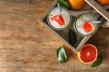 Glasses of refreshing grapefruit lemonade in wooden basket on table, top view