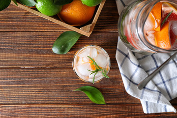 Jug and glass with refreshing grapefruit lemonade on wooden table, top view