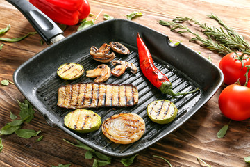 Pan with tasty grilled vegetables on  wooden table