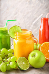 Glassware of tasty smoothies with fruits on grey table