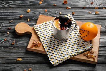 Metal cup of delicious mulled wine on wooden board
