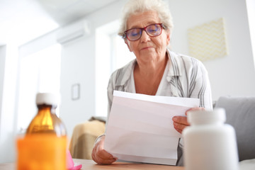 Senior woman reading instruction before taking medicines at home
