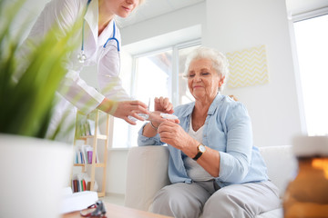 Fototapeta premium Doctor giving medicine to senior woman at home