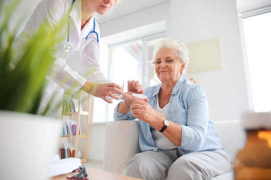 Doctor Giving Medicine To Senior Woman At Home