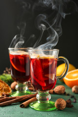 Glass cups of delicious hot mulled wine on color table