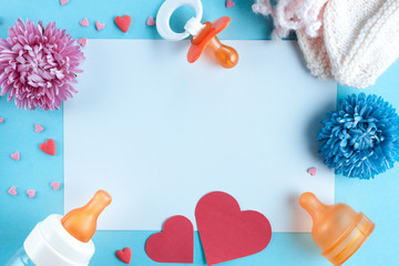 Pregnancy concept. A nipple, a bottle for feeding, socks for a newborn, flowers and hearts on a blue background. Waiting for the baby, future motherhood. Copy space, flat lay. The birth of a boy