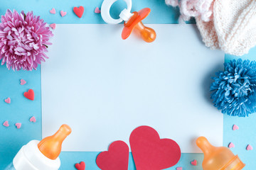 Pregnancy concept. A nipple, a bottle for feeding, socks for a newborn, flowers and hearts on a blue background. Waiting for the baby, future motherhood. Copy space, flat lay. The birth of a boy