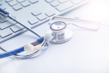 Stethoscope with clipboard and Laptop on desk