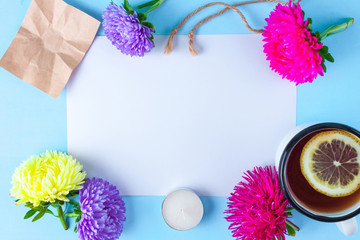 Flower concept. Frame for text on a background of flowers, hot tea with lemon, candles on a blu000e background. Flat lay, copy space. Top view. Flat lay flower. Spring concept