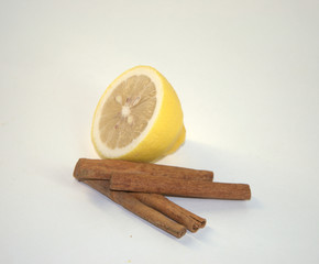 Ripe lemon and cinnamon pods in a closeup on a white background.