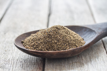 allspice in wooden ladle on wood background.