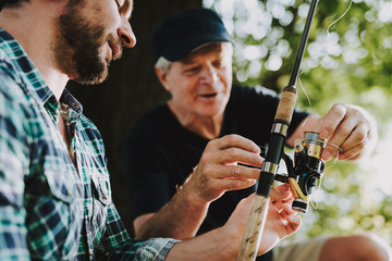 Old Father with Bearded Son Fishing on River.