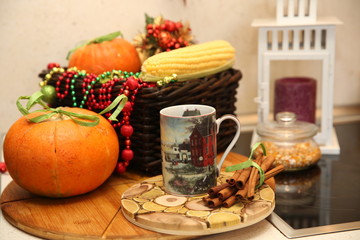 Obraz na płótnie Canvas Fresh pumpkin and corn with decoration and coffee mag and candle in the kitchen. Autumn still life.