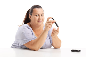 Overweight woman measuring her blood sugar level with a glucometer