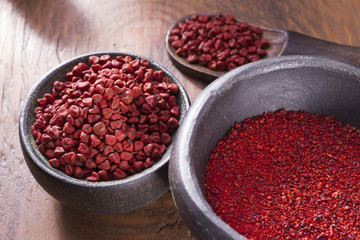 Annatto beans in bowl on wooden table