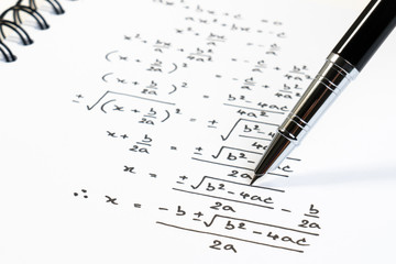 Handwriting of mathematics quadratic equation formula on examination, practice, quiz or test in maths class. Solving exponential equations background concept.