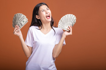 Woman holding cash notes isolated in orange background.