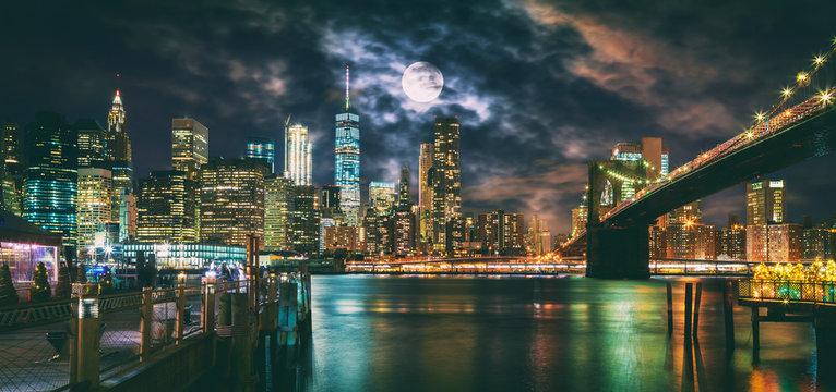 Fototapeta New York City Brooklyn Bridge i Manhattan skyline oświetlone w nocy z pełni księżyca nad głową.